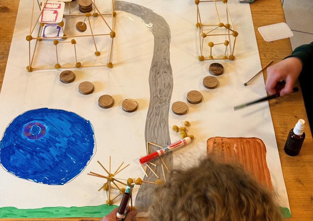View from above of a built model landscape of bamboo and cards on a sheet.