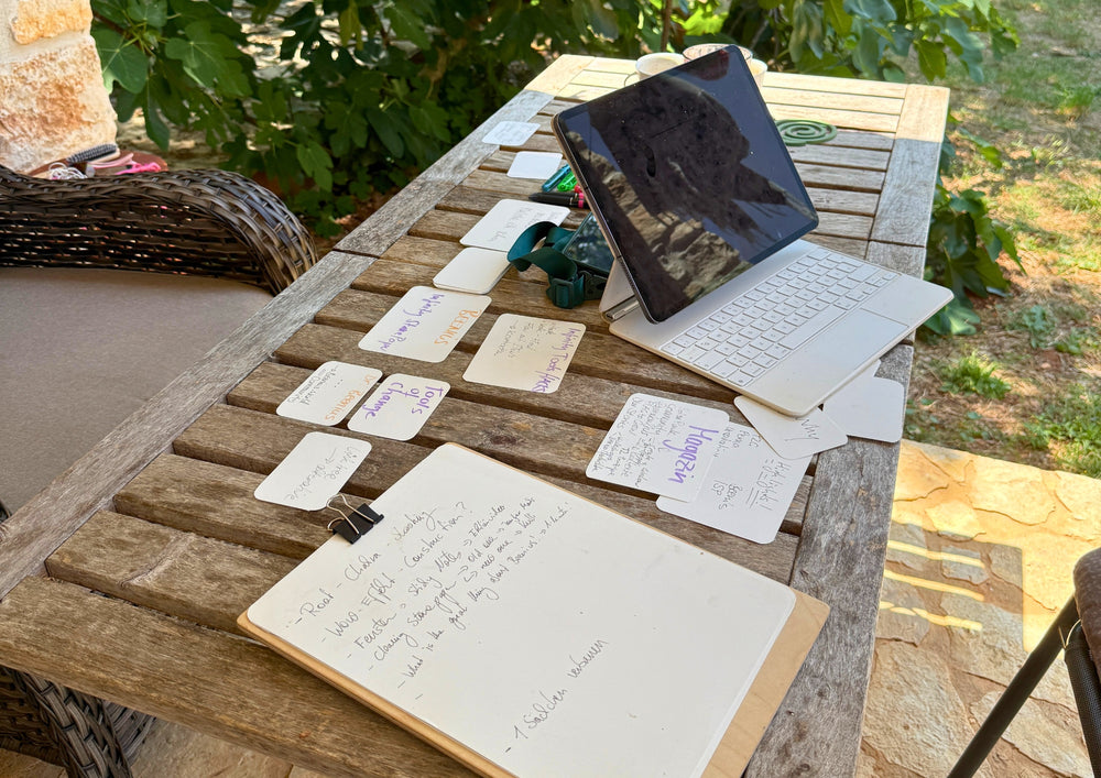 Laptop and written cards side by side on a wooden table in the garden.