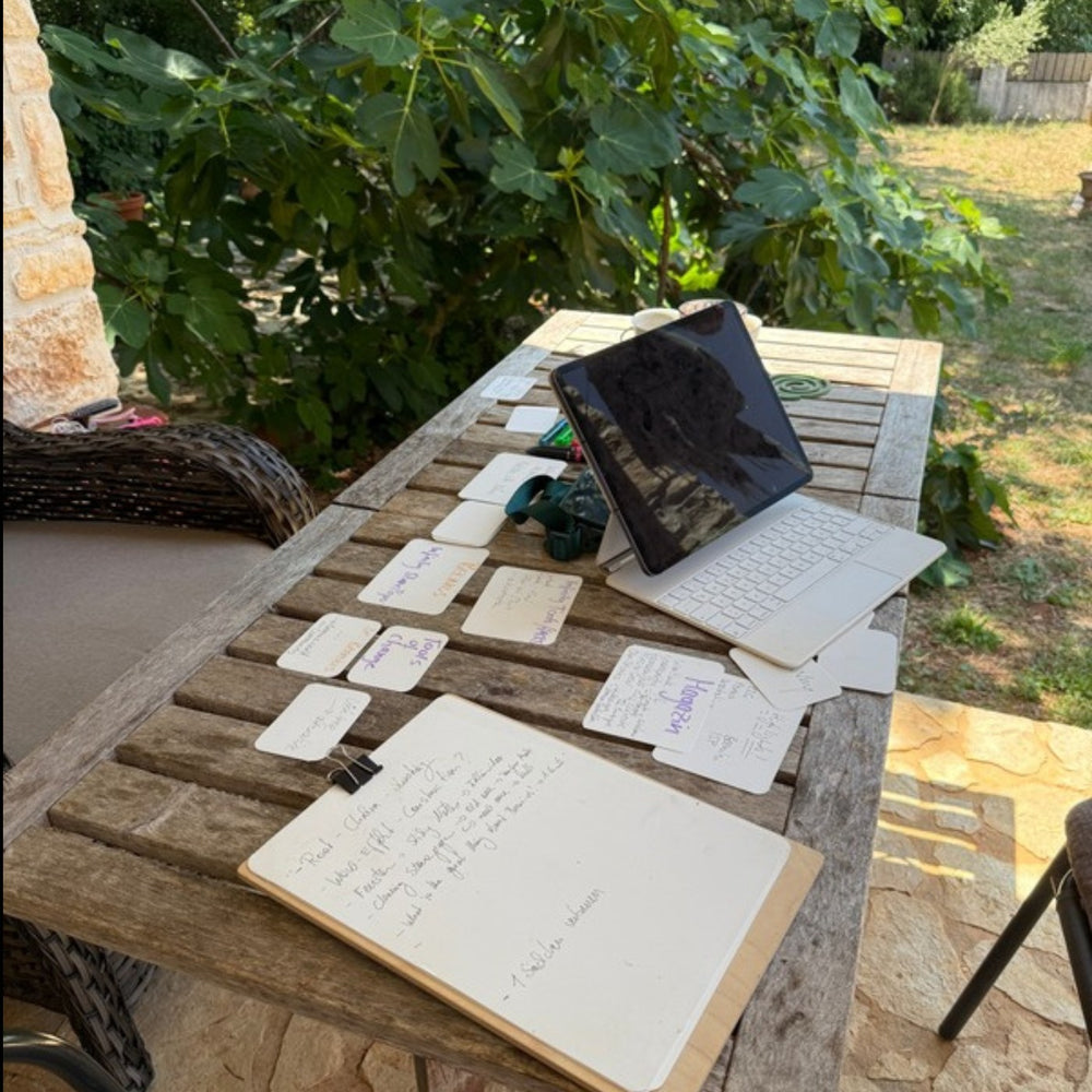 Written Notes and a phone lying on a garden table outdoors.
