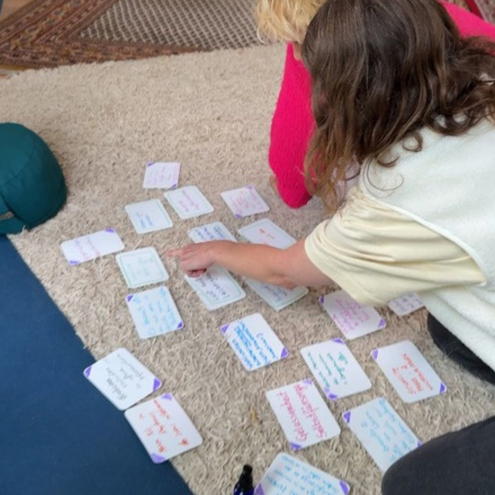 Hands sorting written cards on a carpet.