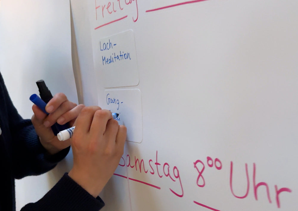 Hand writing on a large board on which a smaller card adheres.