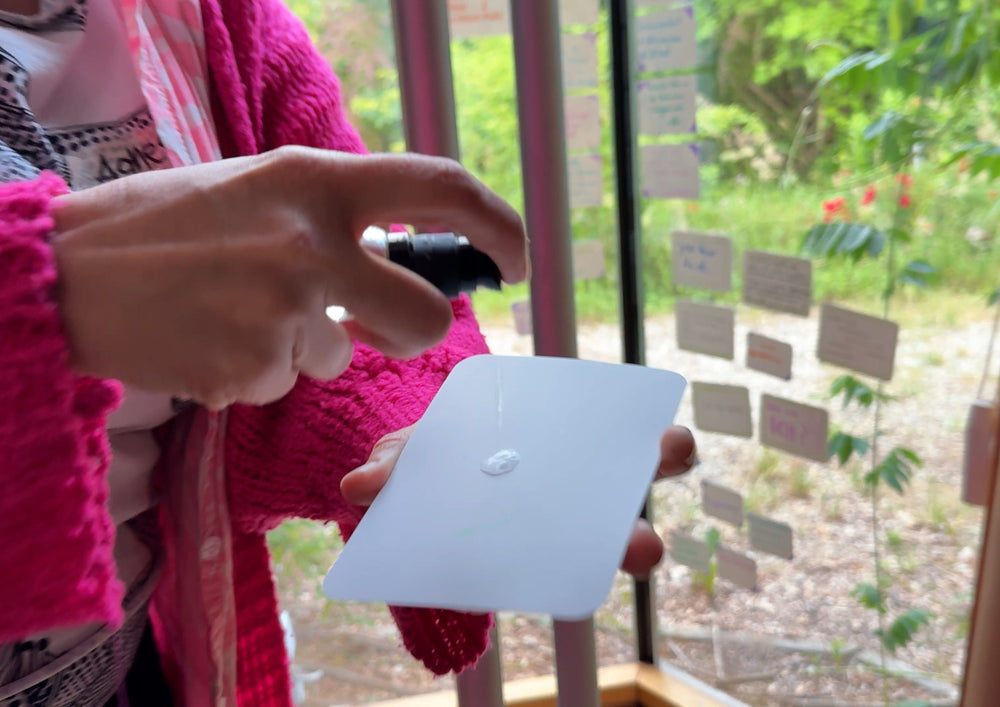 Person putting water on the back of a card with a small bottle.