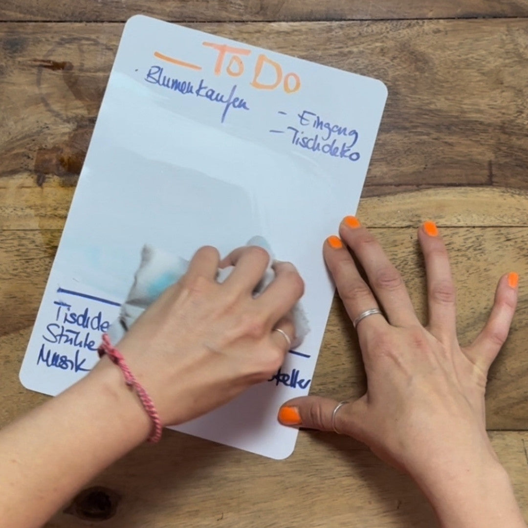 Eine Hand wischt Notizen von einem Bogen Infinity Stonepaper, die Fläche wird wieder leer