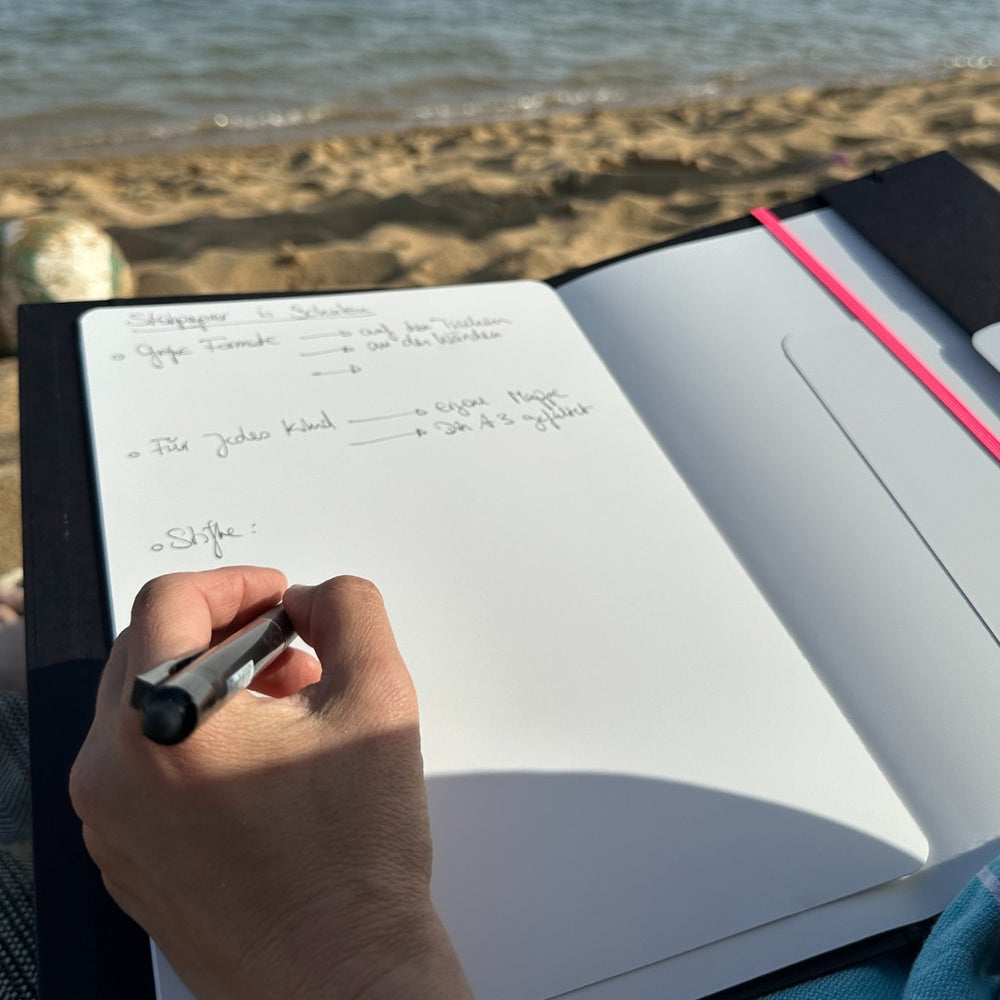 Hand writing in the opened folder on the beach.