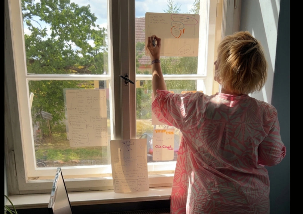 Woman attaching a written card to the window, more sheets hanging on the pane.