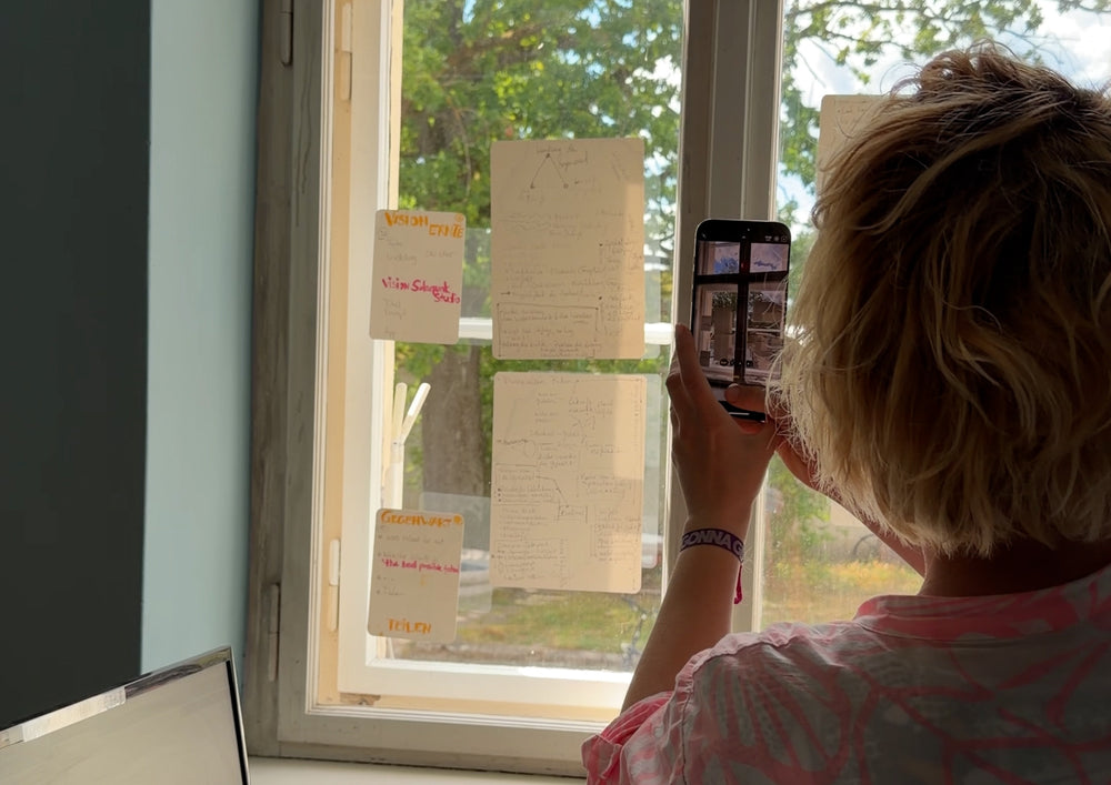 Woman photographing cards on the window with her phone against the light.