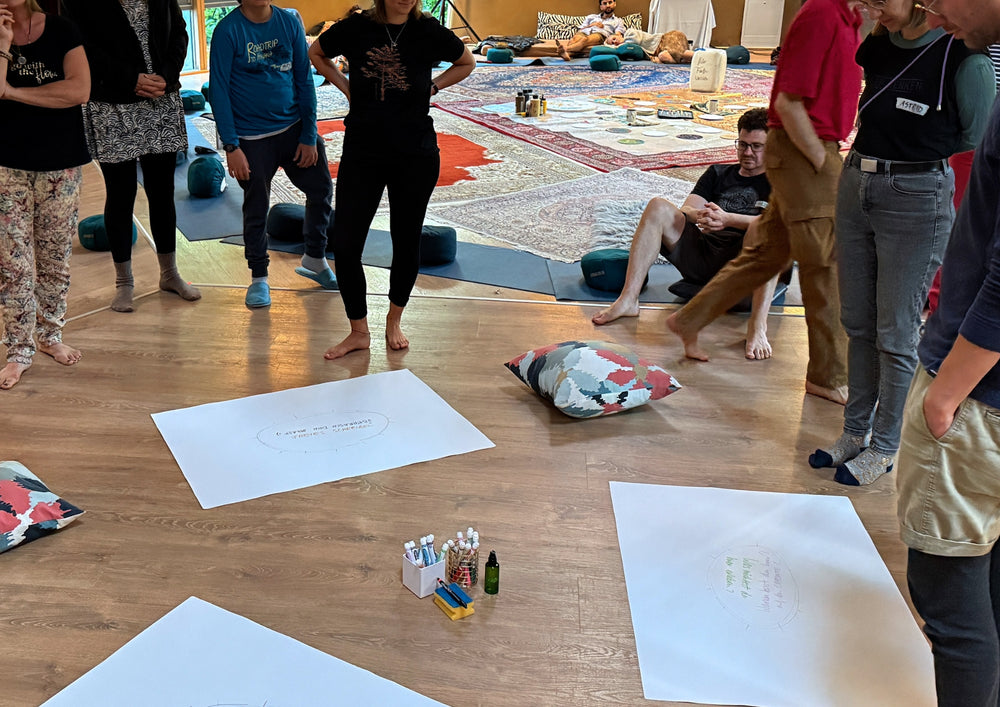 Group standing around large sheets laid out on the floor of a room.