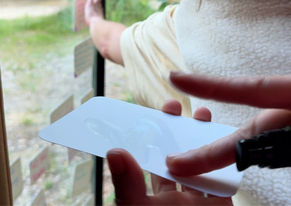 Hands pressing a damp card onto a window pane.
