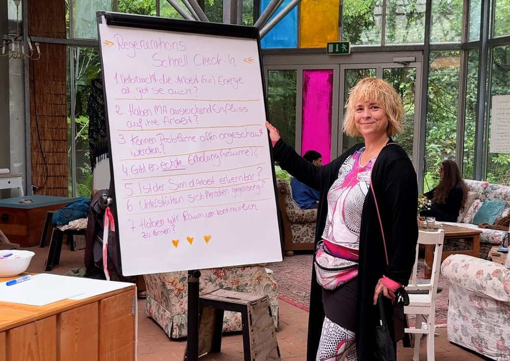 A woman standing next to a flipchart stand with a written sheet on it.