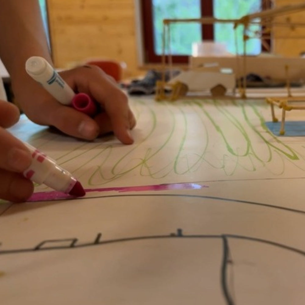 Hand zeichnet mit einem bunten Marker auf einem großen Blatt Steinpapier